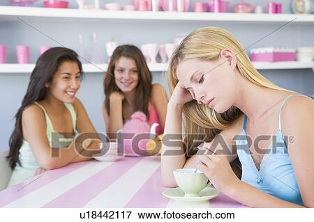 Young woman with a hangover sitting at a table with two friends View Large Photo Image Stock Photo - Young woman with a hangover sitting at a table with two friends. Fotosearch