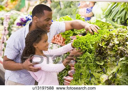 Stock Photo - Father and daughter shopping for lettuce at a grocery store. Fotosearch