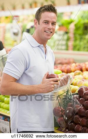 Man shopping for apples at a grocery store View Large Photo Image Stock Image - Man shopping for apples at a grocery store. Fotosearch
