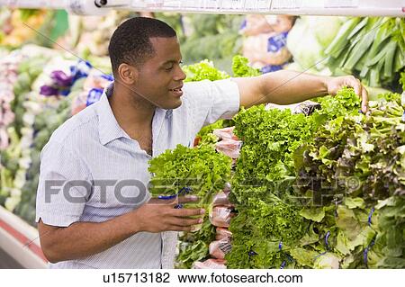 Stock Image - Man shopping for lettuce at a grocery store. Fotosearch