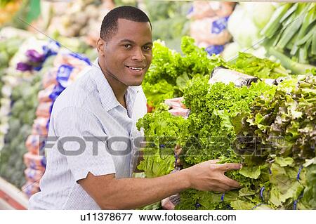 Stock Photo - Man shopping for lettuce at a grocery store. Fotosearch