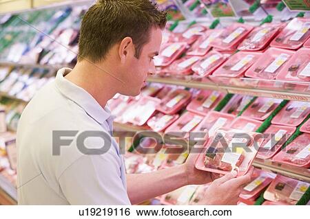 Stock Photograph - Man shopping for meat at a grocery store. Fotosearch