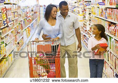 Stock Image - Mother and father with young daughter shopping at the grocery store.. Fotosearch