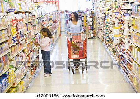 Stock Photograph - Mother and young daughter shopping at a grocery store. Fotosearch