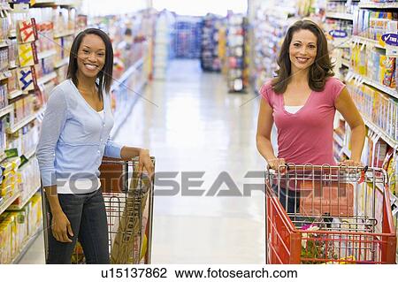 Two women talking to each other at a grocery store View Large Photo Image Stock Image - Two women talking to each other at a grocery store. Fotosearch