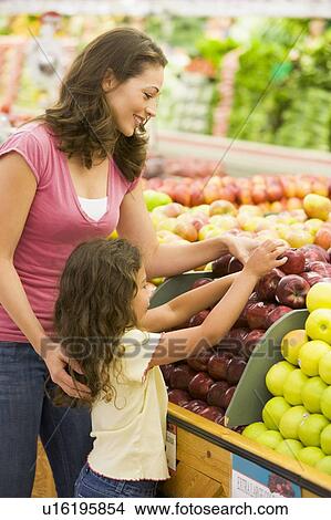 Woman and daughter shopping for apples at a grocery store View Large Photo Image Picture - Woman and daughter shopping for apples at a grocery store. Fotosearch