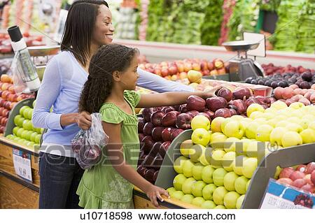 Woman and daughter shopping for apples at a grocery store View Large Photo Image Stock Photo - Woman and daughter shopping for apples at a grocery store. Fotosearch
