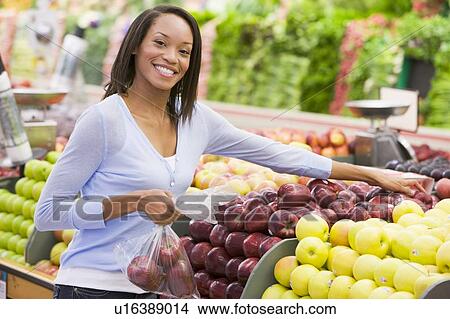 Picture - Woman shopping for apples at a grocery store. Fotosearch