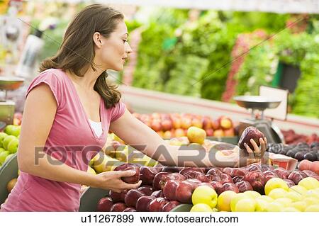 Woman shopping for apples at a grocery store View Large Photo Image Stock Photo - Woman shopping for apples at a grocery store. Fotosearch