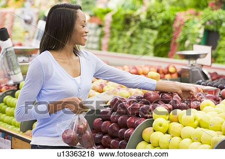 Stock Photo - Woman shopping for apples at a grocery store. Fotosearch