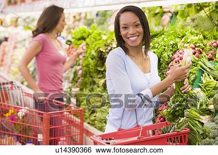 Stock Photograph - Women shopping for vegetables at a grocery store. Fotosearch