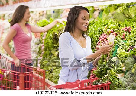 Women shopping for vegetables at a grocery store View Large Photo Image Stock Photograph - Women shopping for vegetables at a grocery store. Fotosearch