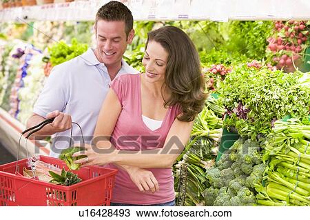 Stock Image - Young couple shopping for broccoli at a grocery store. Fotosearch