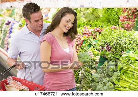Stock Image - Young couple shopping for broccoli at a grocery store. Fotosearch