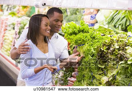 Young couple shopping for lettuce at a grocery store View Large Photo Image Stock Photo - Young couple shopping for lettuce at a grocery store. Fotosearch