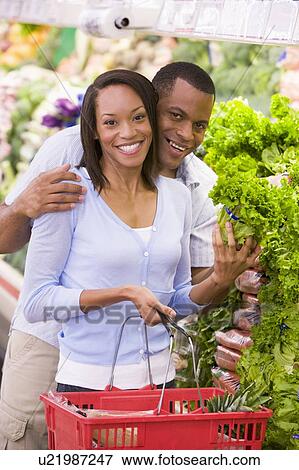 Stock Photo - Young couple shopping for lettuce at a grocery store. Fotosearch