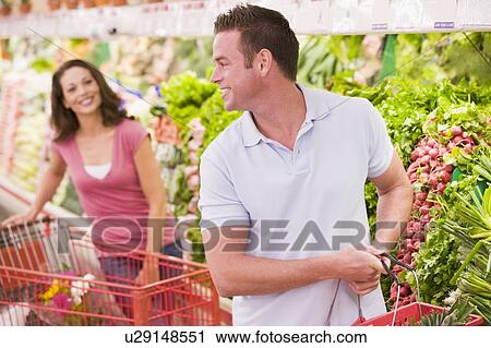 Stock Image - Young couple shopping for vegetables at a grocery store. Fotosearch