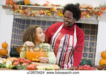 Picture - Grandmother and granddaughter making jack o lantern on Halloween smiling. Fotosearch