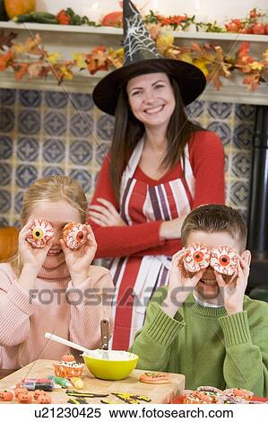 Stock Photography - Mother and two children at Halloween playing with treats and smiling. Fotosearch
