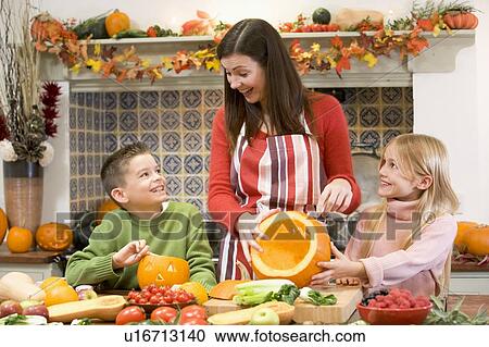 Mother and two children carving jack o lanterns on Halloween and smiling View Large Photo Image Stock Image - Mother and two children carving jack o lanterns on Halloween and smiling. Fotosearch