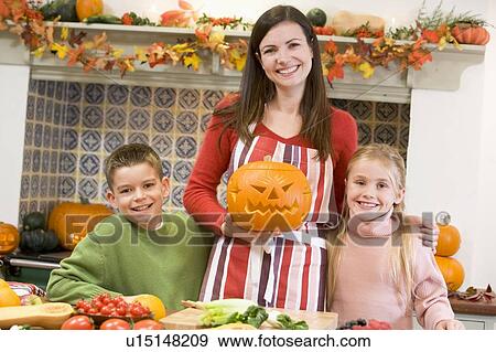Mother and two children carving jack o lanterns on Halloween and smiling View Large Photo Image Stock Photo - Mother and two children carving jack o lanterns on Halloween and smiling. Fotosearch