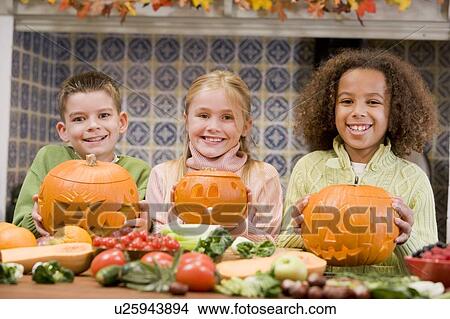 Three young friends on Halloween with jack o lanterns and food smiling View Large Photo Image Picture - Three young friends on Halloween with jack o lanterns and food smiling. Fotosearch
