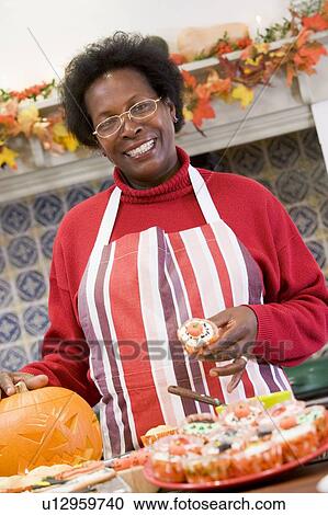 Woman in kitchen making Halloween treats and smiling View Large Photo Image Stock Image - Woman in kitchen making Halloween treats and smiling. Fotosearch