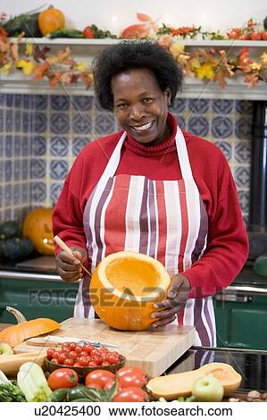 Stock Image - Woman on Halloween making jack o lantern smiling. Fotosearch