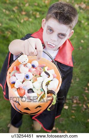 Young boy outdoors wearing vampire costume on Halloween holding candy View Large Photo Image Stock Image - Young boy outdoors wearing vampire costume on Halloween holding candy. Fotosearch