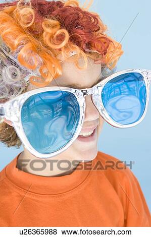 Stock Photo - Young boy wearing clown wig and sunglasses smiling. Fotosearch