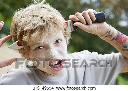 Young boy with scary Halloween make up and plastic knife through head View Large Photo Image Picture - Young boy with scary Halloween make up and plastic knife through head. Fotosearch