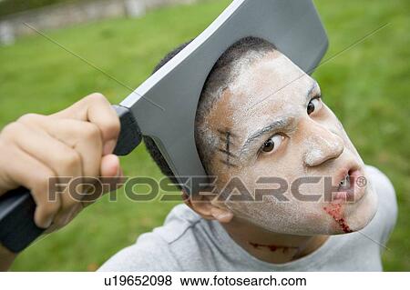 Stock Photo - Young boy with scary Halloween make up and plastic knife through head. Fotosearch