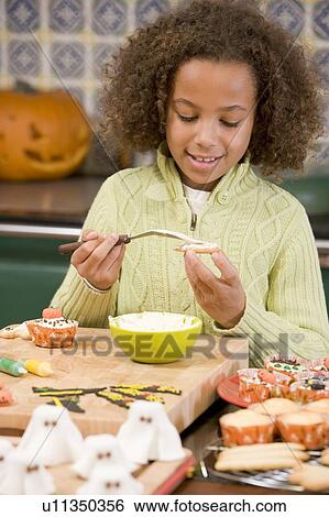 Young girl at Halloween making treats and smiling View Large Photo Image Stock Photograph - Young girl at Halloween making treats and smiling. Fotosearch