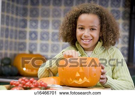 Stock Image - Young girl on Halloween with jack o lantern smiling. Fotosearch