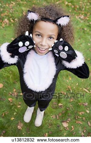 Stock Image - Young girl outdoors in cat costume on Halloween. Fotosearch