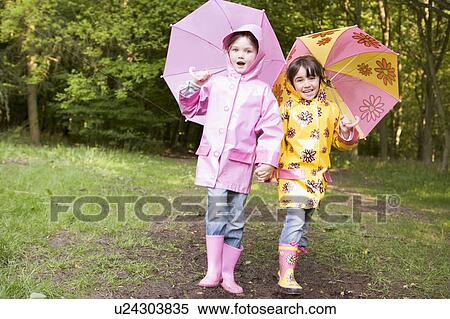 Two sisters outdoors with umbrellas smiling View Large Photo Image Stock Photography - Two sisters outdoors with umbrellas smiling. Fotosearch