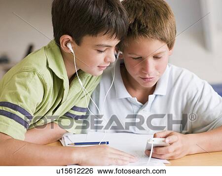 Two Young Boys Distracted From Their Homework, Playing With An MP3 Player View Large Photo Image Stock Photograph - Two Young Boys Distracted From Their Homework, Playing With An MP3 Player. Fotosearch
