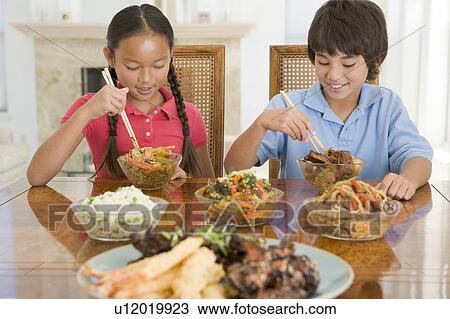 Two young children eating chinese food in dining room smiling View Large Photo Image Stock Image - Two young children eating chinese food in dining room smiling. Fotosearch