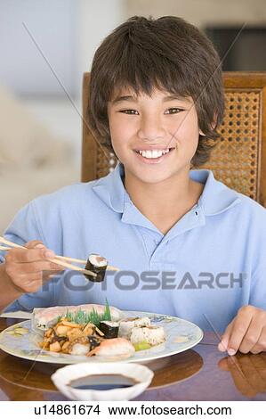 Young boy in dining room eating chinese food smiling View Large Photo Image Picture - Young boy in dining room eating chinese food smiling. Fotosearch