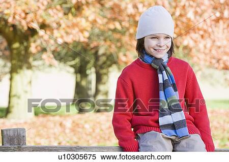 Young boy outdoors at park sitting on fence smiling (selective focus) View Large Photo Image Stock Photography - Young boy outdoors at park sitting on fence smiling (selective focus). Fotosearch