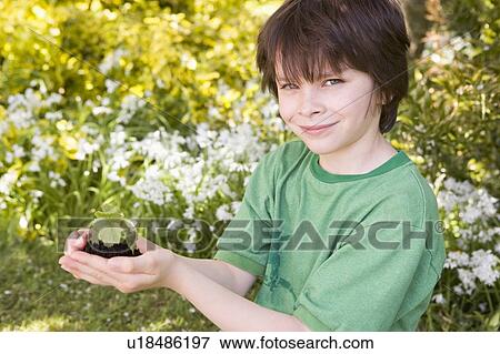 Young boy outdoors holding plant smiling View Large Photo Image Stock Photo - Young boy outdoors holding plant smiling. Fotosearch