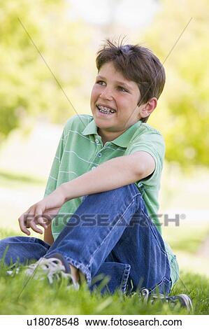 Young boy sitting outdoors smiling View Large Photo Image Stock Photo - Young boy sitting outdoors smiling. Fotosearch