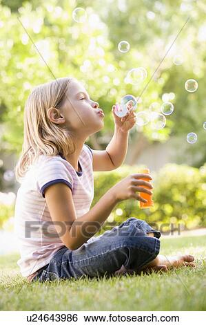 Stock Photograph - Young girl blowing bubbles outdoors. Fotosearch