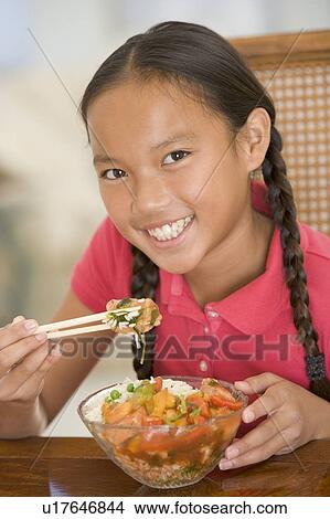 Young girl in dining room eating chinese food smiling View Large Photo Image Picture - Young girl in dining room eating chinese food smiling. Fotosearch
