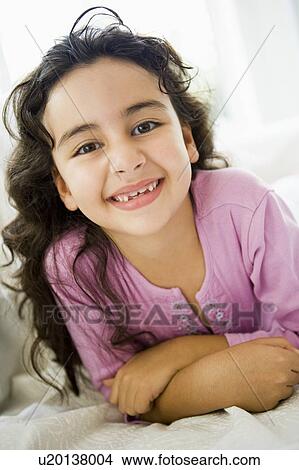 Young girl in living room smiling (high key) View Large Photo Image Picture - Young girl in living room smiling (high key). Fotosearch