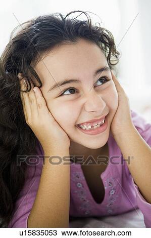 Stock Image - Young girl in living room smiling (high key/selective focus). Fotosearch