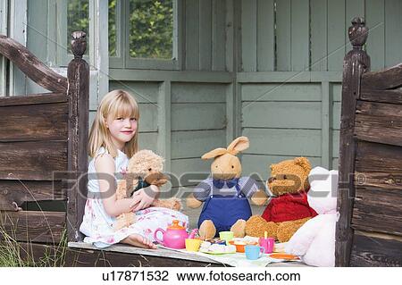 Stock Image - Young girl in shed playing tea and smiling. Fotosearch