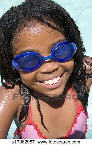 Stock Photo - Young girl in swimming pool wearing goggles smiling. Fotosearch