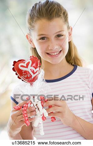 Young girl on Valentine's Day holding love themed balloon smiling View Large Photo Image Stock Photography - Young girl on Valentine's Day holding love themed balloon smiling. Fotosearch