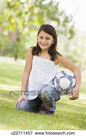 Young girl outdoors at park holding ball and smiling (selective focus) View Large Photo Image Stock Photo - Young girl outdoors at park holding ball and smiling (selective focus). Fotosearch